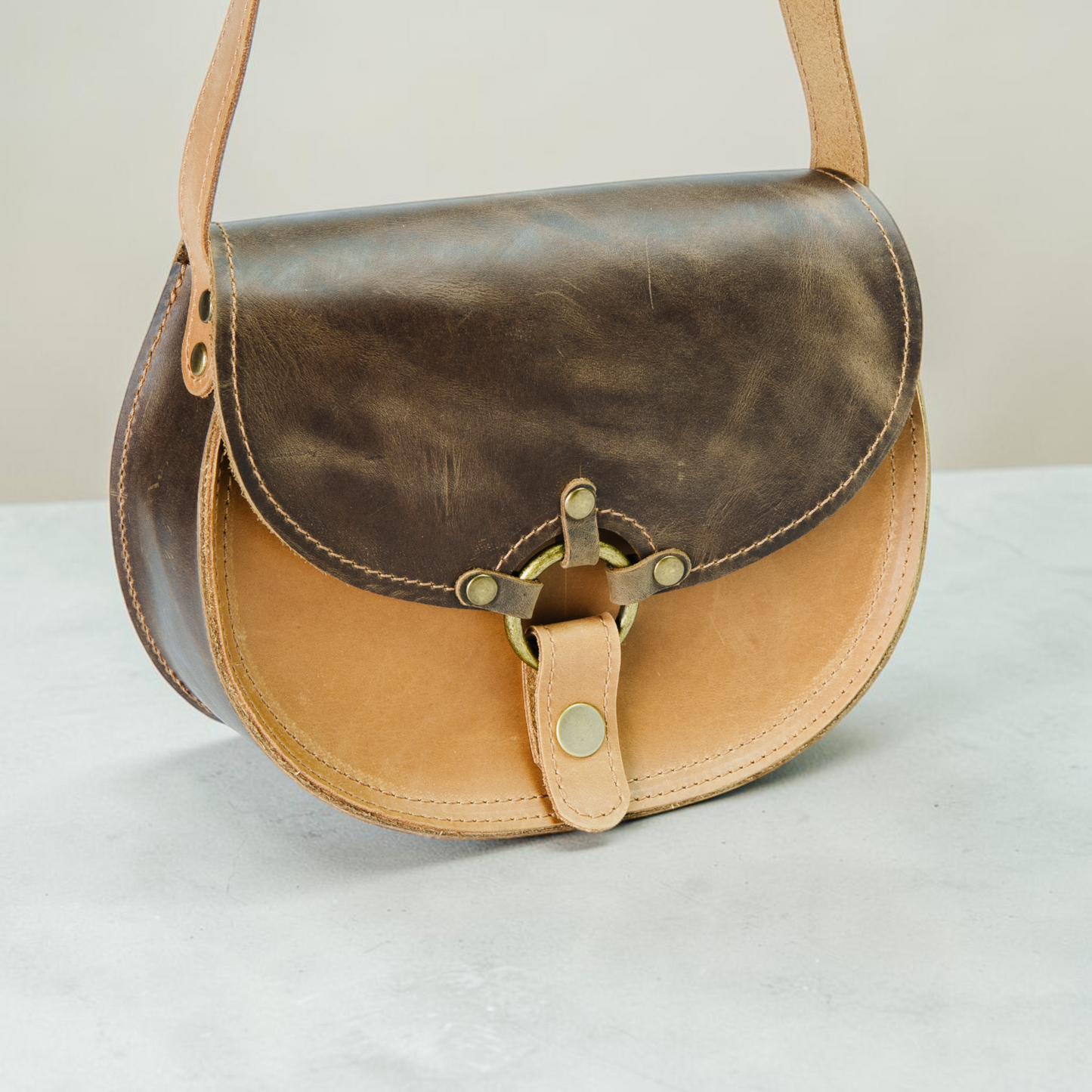 Handgefertigte runde Ledertasche mit Ringverschluss und klarer Satteltaschenform für Damen